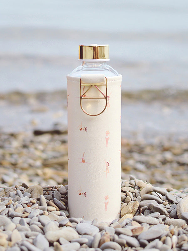 Glazen fles met hoes met personen er op  in kiezel